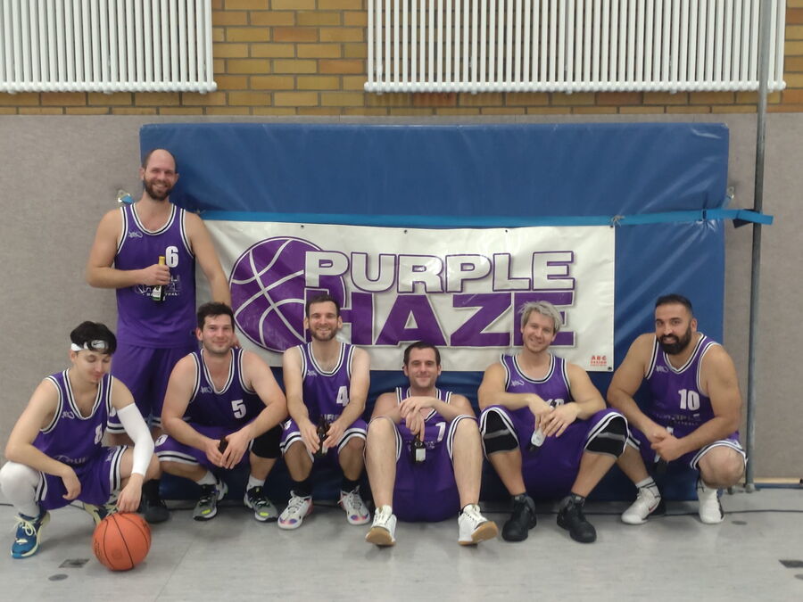 Teamfoto der Basketballer in lila Trikots vor einem Banner